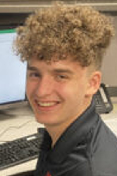 A young man smiling in front of a computer