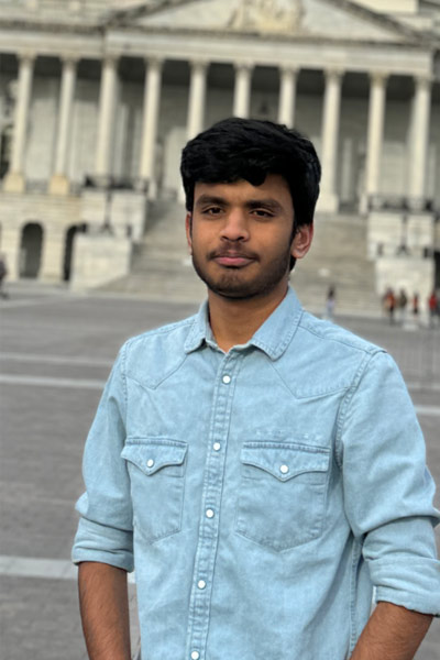 A three quarter portrait of a young man smiling while standing in front of the US Capitol building in Washington D.C..