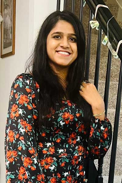 A three quarter portrait of a young woman smiling while standing indoors of her home.