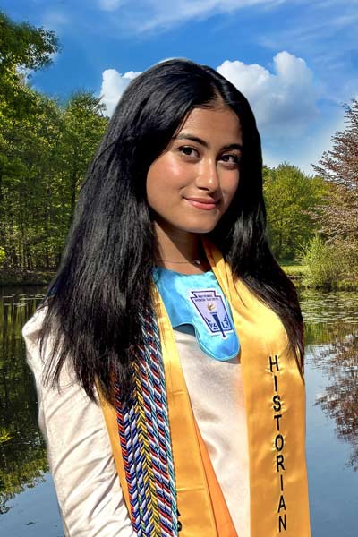 A young woman smiling while standing outside near a lake.