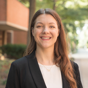 A professional woman smiling while standing in a breezeway.