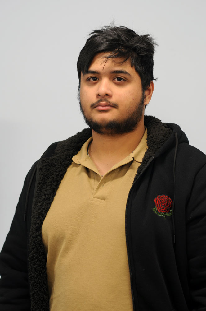 A three quarter portrait of a young man frowning.