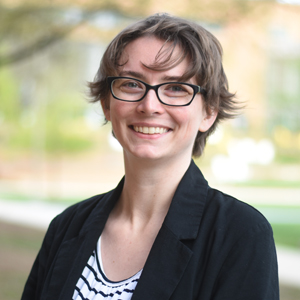 A young college staffer smiling outside in a courtyard
