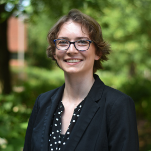 A young college staffer smiling outside in a courtyard