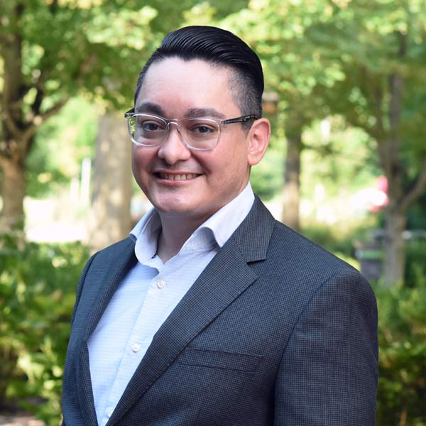 College staffer smiling outside in a courtyard