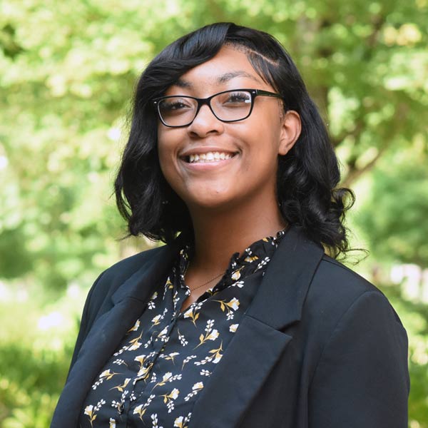 College staffer smiling outside in a courtyard