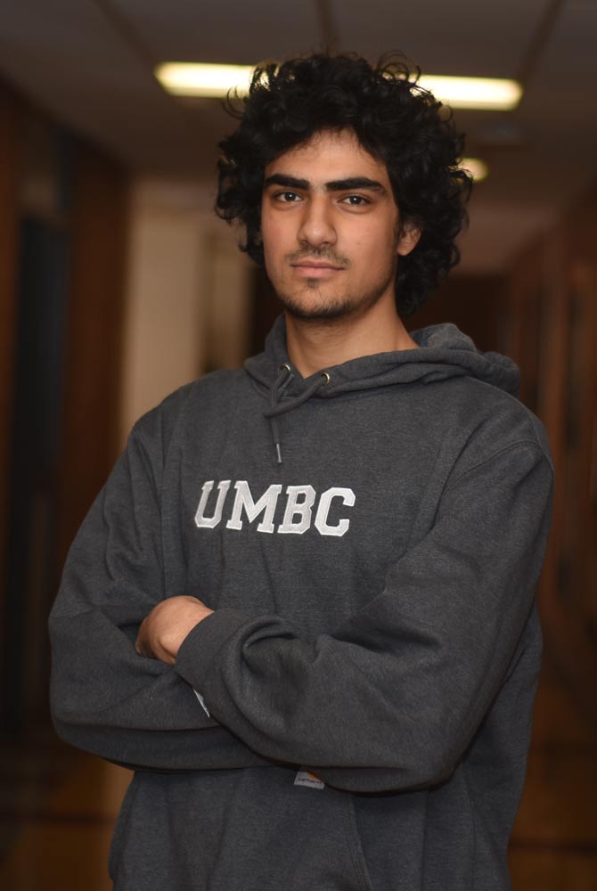 Shayan is standing in front of the academic success center's ofices, he is smiling